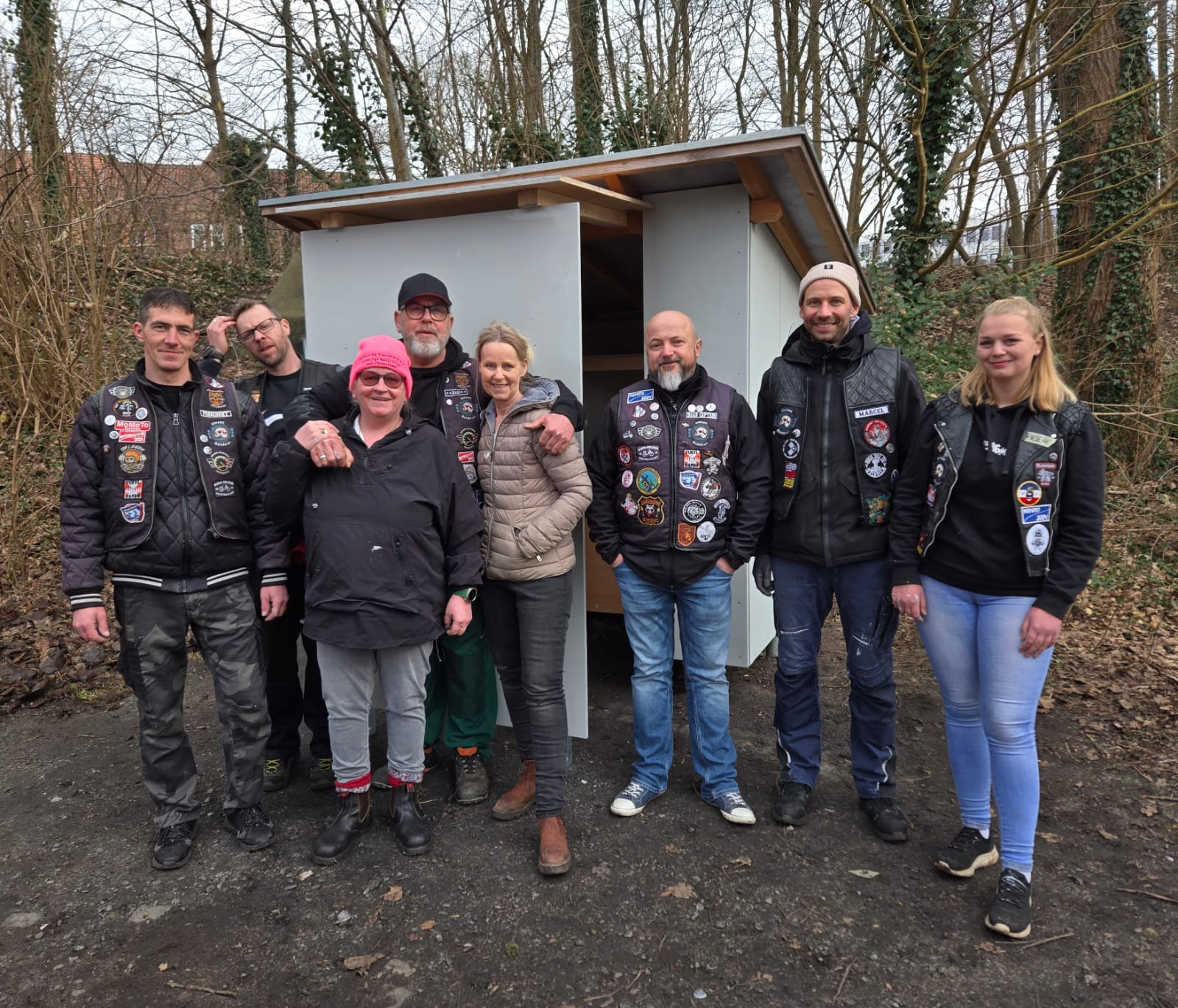 Große Gruppe von Helferinnen und Helfern vor der fertigen weißen Schutzhütte