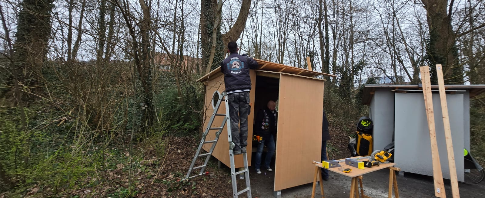 Helfer arbeitet von der Leiter am Dach der Holzhütte