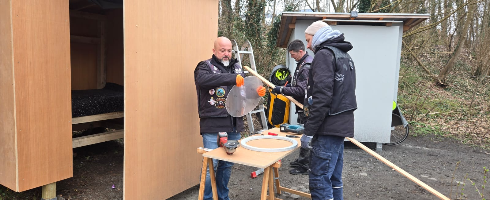 Helfer prüft die runde Fensterscheibe vor der Hütte