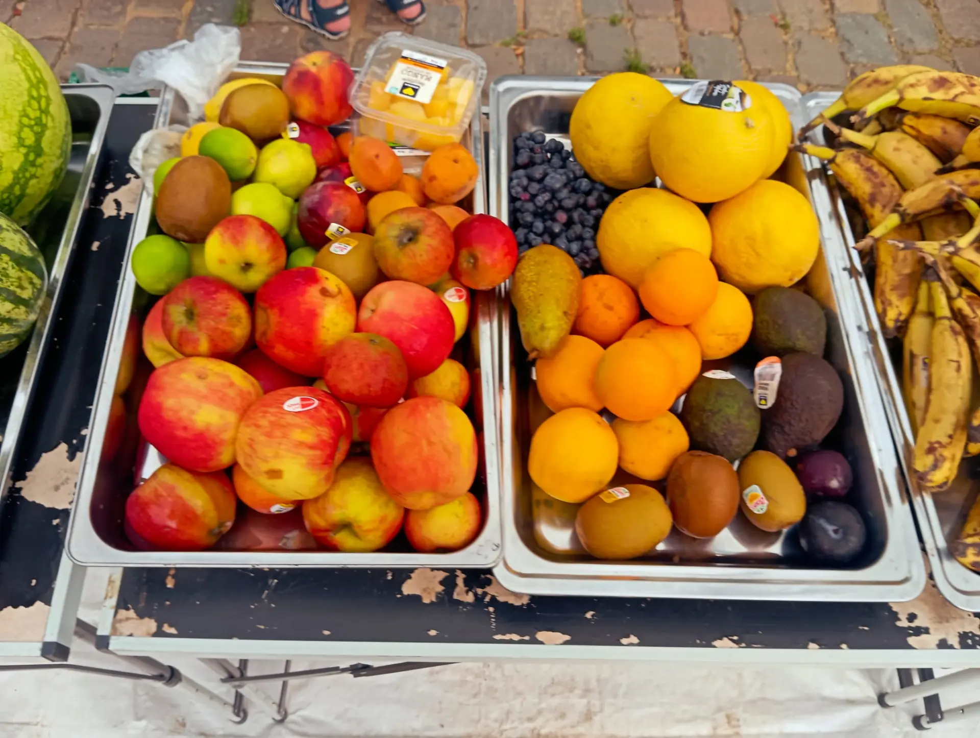 Schalen mit Äpfeln, Orangen, Kiwis und Bananen auf dem Ausgabetisch