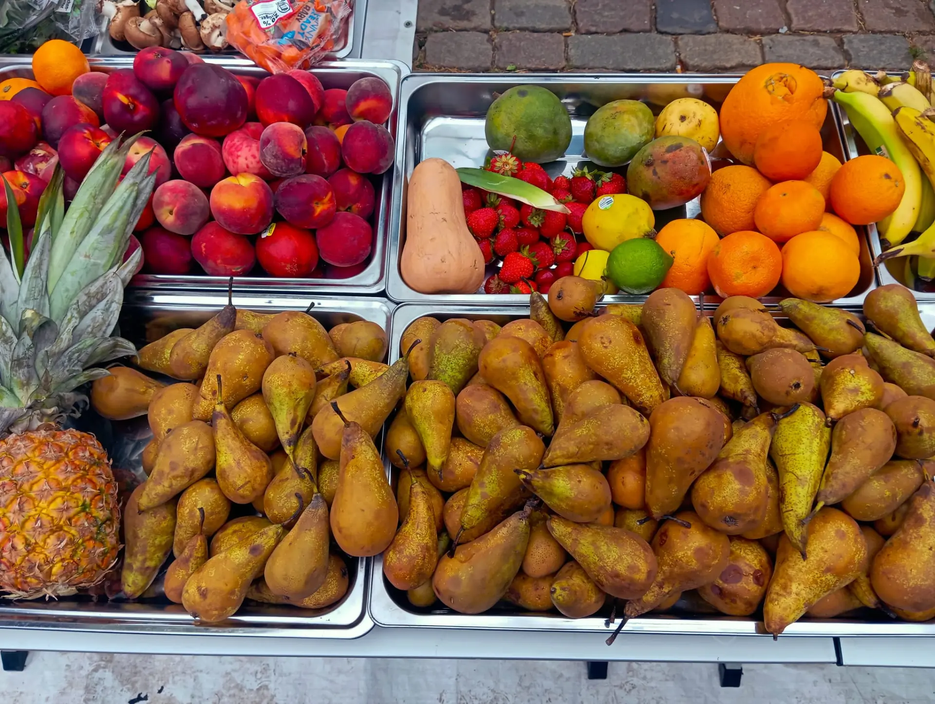 Birnen, Nektarinen, Erdbeeren und Ananas in Auslagen