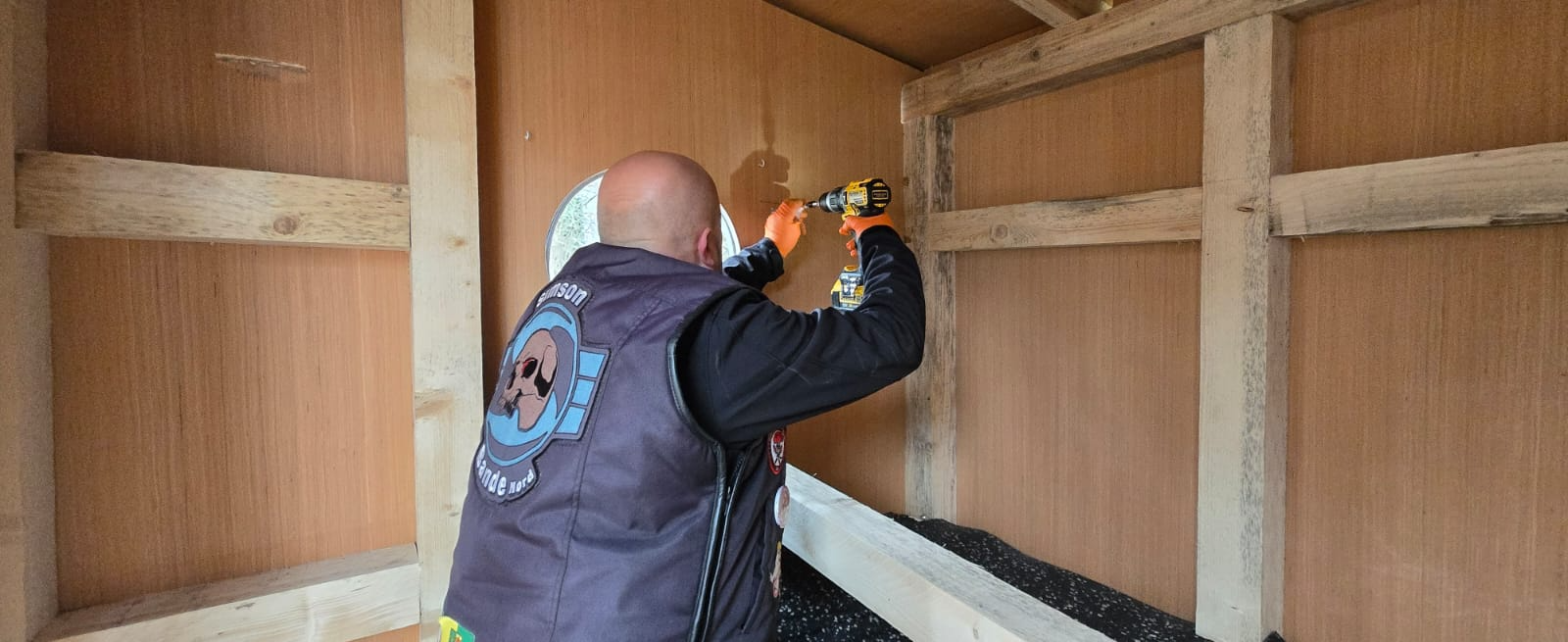 Helfer verschraubt im Inneren der Hütte die Holzverkleidung