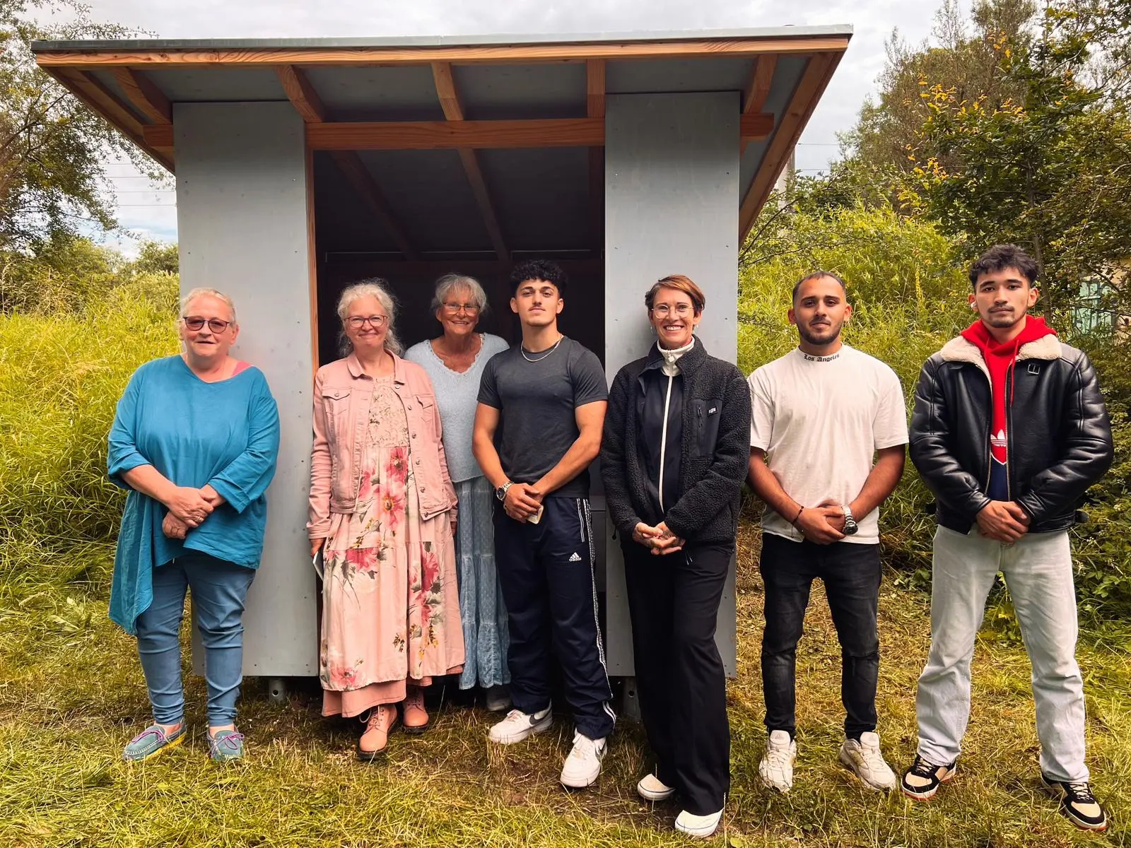 Sieben Helferinnen und Helfer vor der fertigen Schutzhütte im Grünen