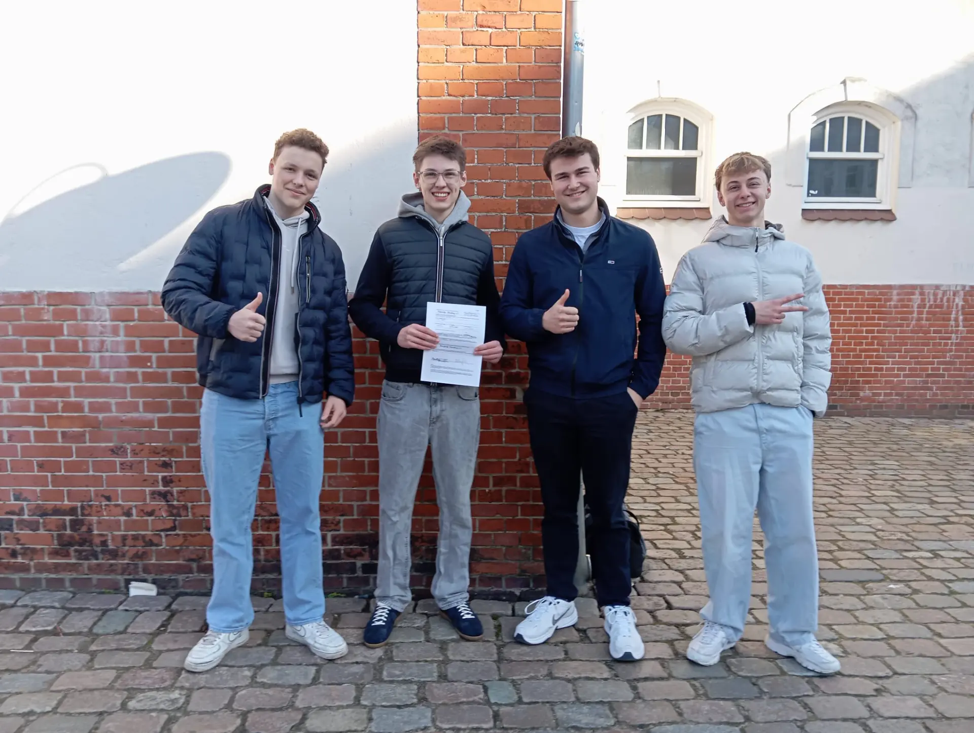 Vier junge Männer mit einem unterschriebenen Dokument