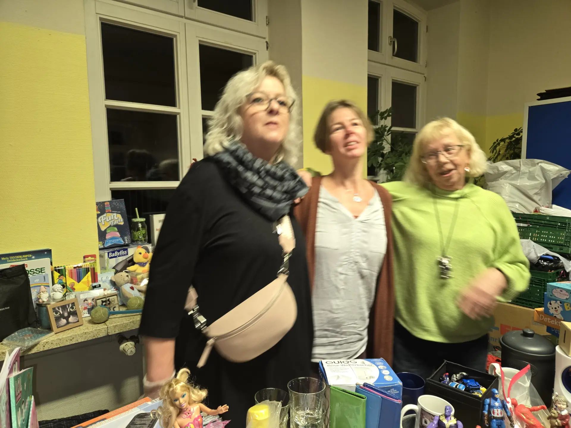 Drei Helferinnen hinter Tischen mit Spielzeug und Geschenken